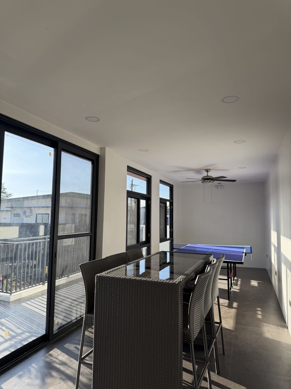 A ping-pong table on the upper deck beside bar stools and glass doors