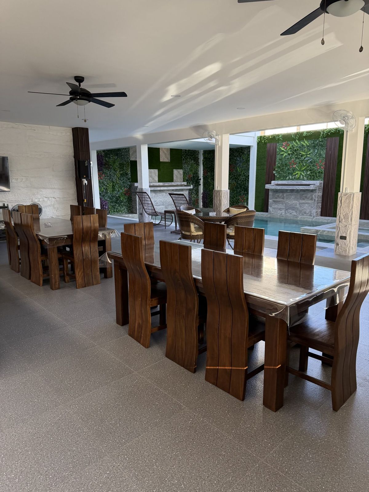 A long wooden table set for ten with the pool just beyond it